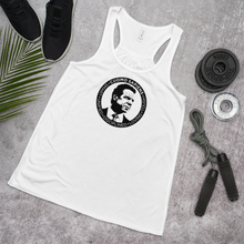 Load image into Gallery viewer, A women’s flowy, racerback style tank top, in white, lying flat on the floor with some exercise equipment, featuring the Cuomo Sapiens S.U.D.L.T. SEAL graphic in white.