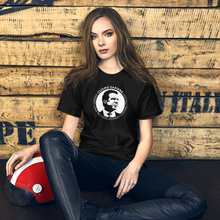 Load image into Gallery viewer, Woman with a scooter helmet next to some crates, wearing a black unisex t-shirt, featuring the Cuomo Sapiens S.U.D.L.T. SEAL graphic in white.