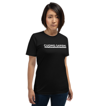 Load image into Gallery viewer, Woman wearing a black unisex t-shirt, featuring the Cuomo Sapiens S.U.D.L.T. graphic in white.