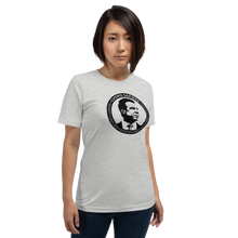 Load image into Gallery viewer, Woman wearing a heather grey unisex t-shirt, featuring the Cuomo Sapiens S.U.D.L.T. SEAL graphic in black.