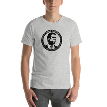 Load image into Gallery viewer, Man wearing a heather grey unisex t-shirt, featuring the Cuomo Sapiens S.U.D.L.T. SEAL graphic in black.