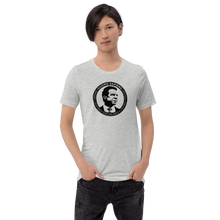 Load image into Gallery viewer, Man wearing a heather grey unisex t-shirt, featuring the Cuomo Sapiens S.U.D.L.T. SEAL graphic in black.