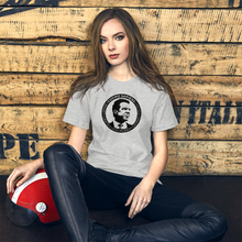 Load image into Gallery viewer, Woman with a scooter helmet next to some crates, wearing a heather grey unisex t-shirt, featuring the Cuomo Sapiens S.U.D.L.T. SEAL graphic in black.