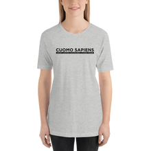 Load image into Gallery viewer, Woman wearing a heather grey unisex t-shirt, featuring the Cuomo Sapiens S.U.D.L.T. graphic in black.