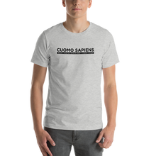 Load image into Gallery viewer, Man wearing a heather grey unisex t-shirt, featuring the Cuomo Sapiens S.U.D.L.T. graphic in black.