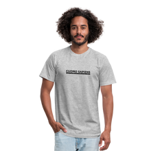 Load image into Gallery viewer, Man wearing a heather grey unisex t-shirt, featuring the Cuomo Sapiens S.U.D.L.T. graphic in black.