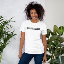 Load image into Gallery viewer, Woman standing next to some plants, wearing a white unisex t-shirt, featuring the Cuomo Sapiens S.U.D.L.T. graphic in black.
