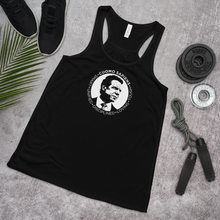 Load image into Gallery viewer, A women’s flowy, racerback style tank top, in black, lying flat on the floor with some exercise equipment, featuring the Cuomo Sapiens S.U.D.L.T. SEAL graphic in white.
