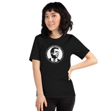 Load image into Gallery viewer, Woman wearing a black unisex t-shirt, featuring the Cuomo Sapiens S.U.D.L.T. SEAL graphic in white.
