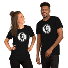 Load image into Gallery viewer, A woman and a man wearing black unisex t-shirts, featuring the Cuomo Sapiens S.U.D.L.T. SEAL graphic in white.
