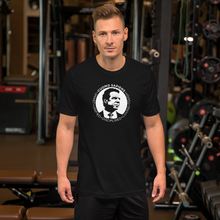 Load image into Gallery viewer, Man at the gym, wearing a black unisex t-shirt, featuring the Cuomo Sapiens S.U.D.L.T. SEAL graphic in white.
