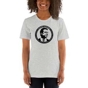 Woman wearing a heather grey unisex t-shirt, featuring the Cuomo Sapiens S.U.D.L.T. SEAL graphic in black.