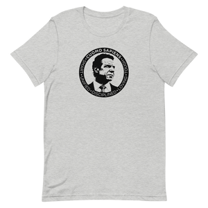 A heather grey unisex t-shirt on a flat surface, featuring the Cuomo Sapiens S.U.D.L.T. SEAL graphic in black.