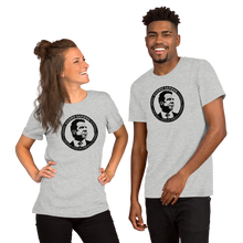 Load image into Gallery viewer, A woman and a man wearing heather grey unisex t-shirts, featuring the Cuomo Sapiens S.U.D.L.T. SEAL graphic in black.
