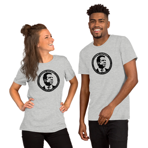 A woman and a man wearing heather grey unisex t-shirts, featuring the Cuomo Sapiens S.U.D.L.T. SEAL graphic in black.