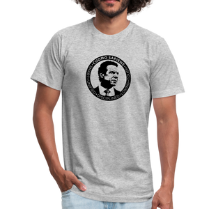 Man wearing a heather grey unisex t-shirt, featuring the Cuomo Sapiens S.U.D.L.T. SEAL graphic in black.