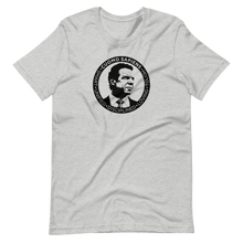 Load image into Gallery viewer, A heather grey unisex t-shirt lying wrinkled on a flat surface, featuring the Cuomo Sapiens S.U.D.L.T. SEAL graphic in black.

