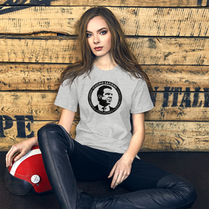 Woman with a scooter helmet next to some crates, wearing a heather grey unisex t-shirt, featuring the Cuomo Sapiens S.U.D.L.T. SEAL graphic in black.