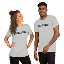 Load image into Gallery viewer, A woman and a man wearing heather grey unisex t-shirts, featuring the Cuomo Sapiens S.U.D.L.T. graphic in black.

