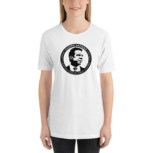 Woman wearing a white unisex t-shirt, featuring the Cuomo Sapiens S.U.D.L.T. SEAL graphic in black.