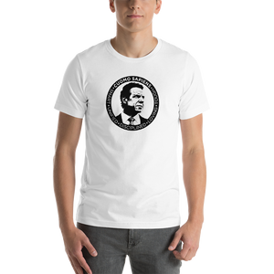Man wearing a white unisex t-shirt, featuring the Cuomo Sapiens S.U.D.L.T. SEAL graphic in black.