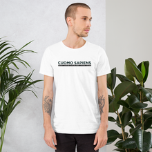 Load image into Gallery viewer, Man standing next to some plants, wearing a white unisex t-shirt, featuring the Cuomo Sapiens S.U.D.L.T. graphic in black.
